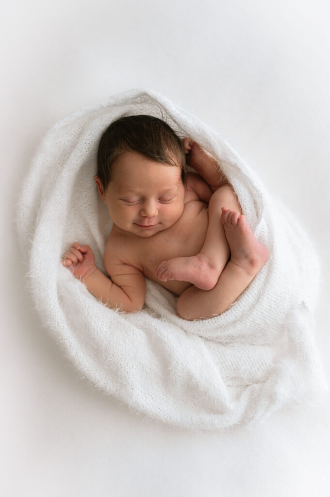 newborn baby girl wrapped up at her newborn photoshoot in york smiling!